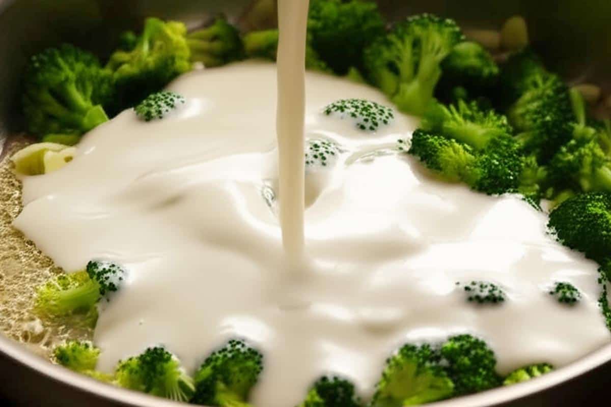 Pouring in the cream over the broccoli.