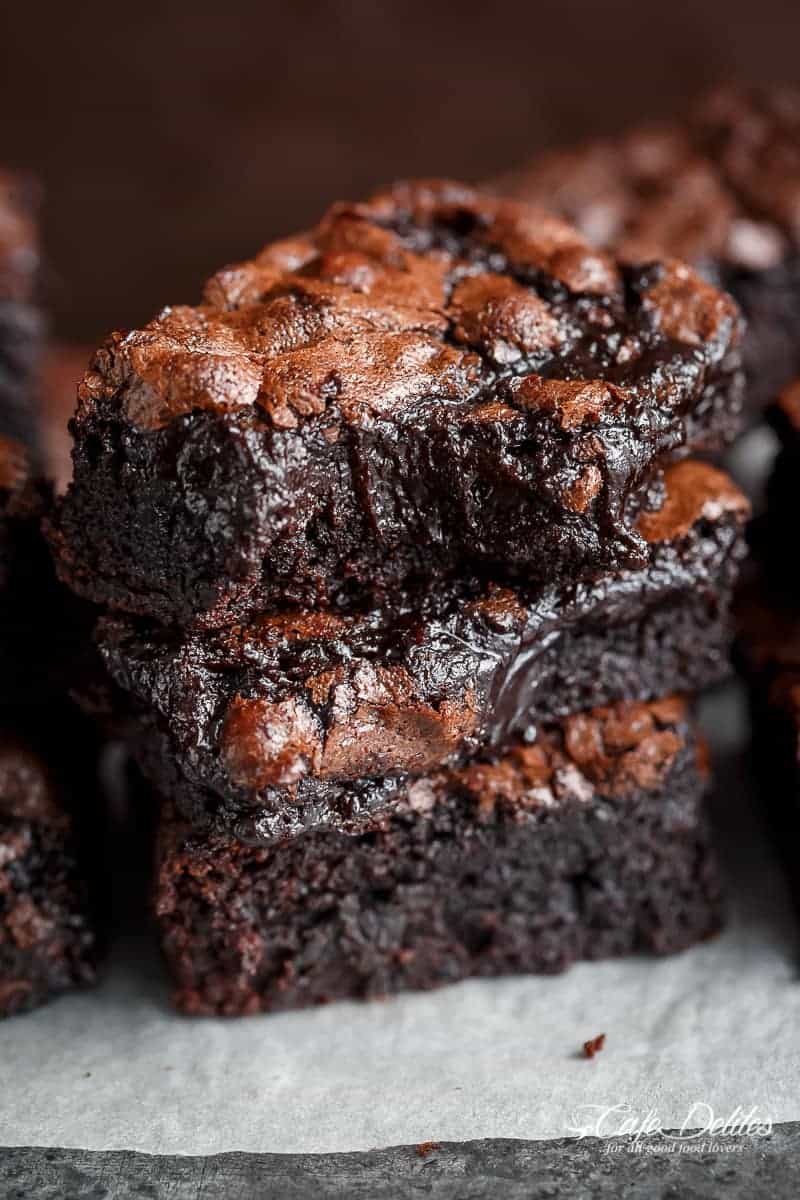 Image of three stacked fudgy brownies, one of which has a bite taken out of it.