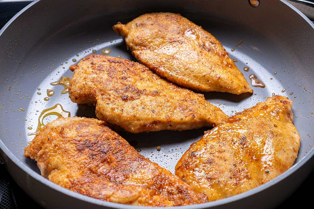 seasoned chicken seared in a pan
