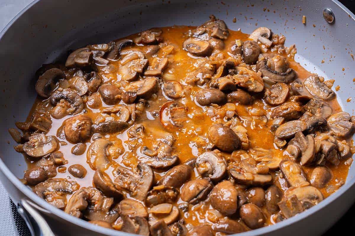 mushrooms and seasonings with stock and wine in a pan