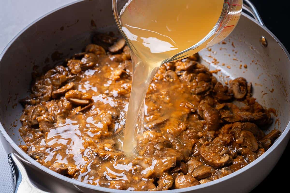 mushrooms and seasonings with stock and wine in a pan with flour