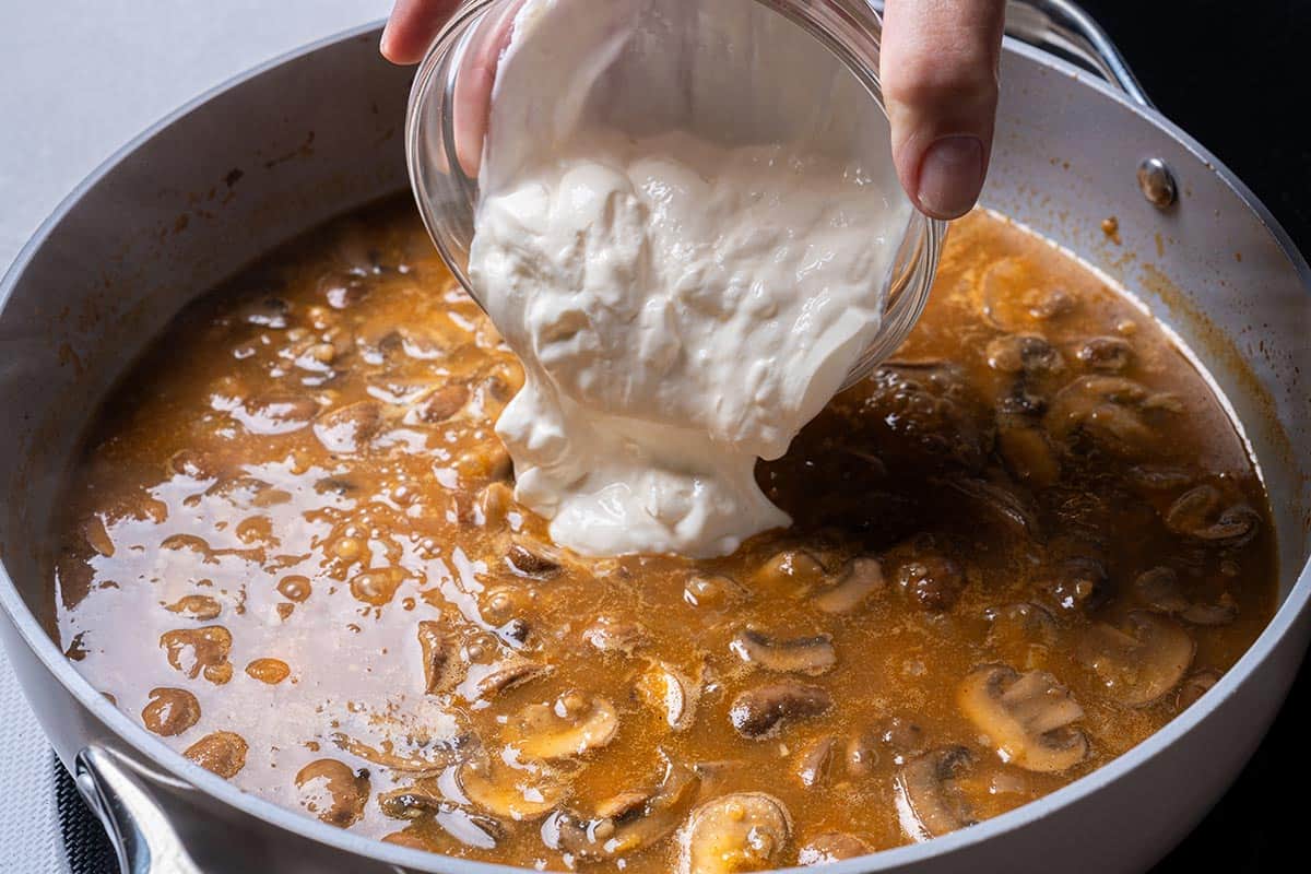 mushrooms and seasonings with stock and wine in a pan with flour and having sour cream poured in