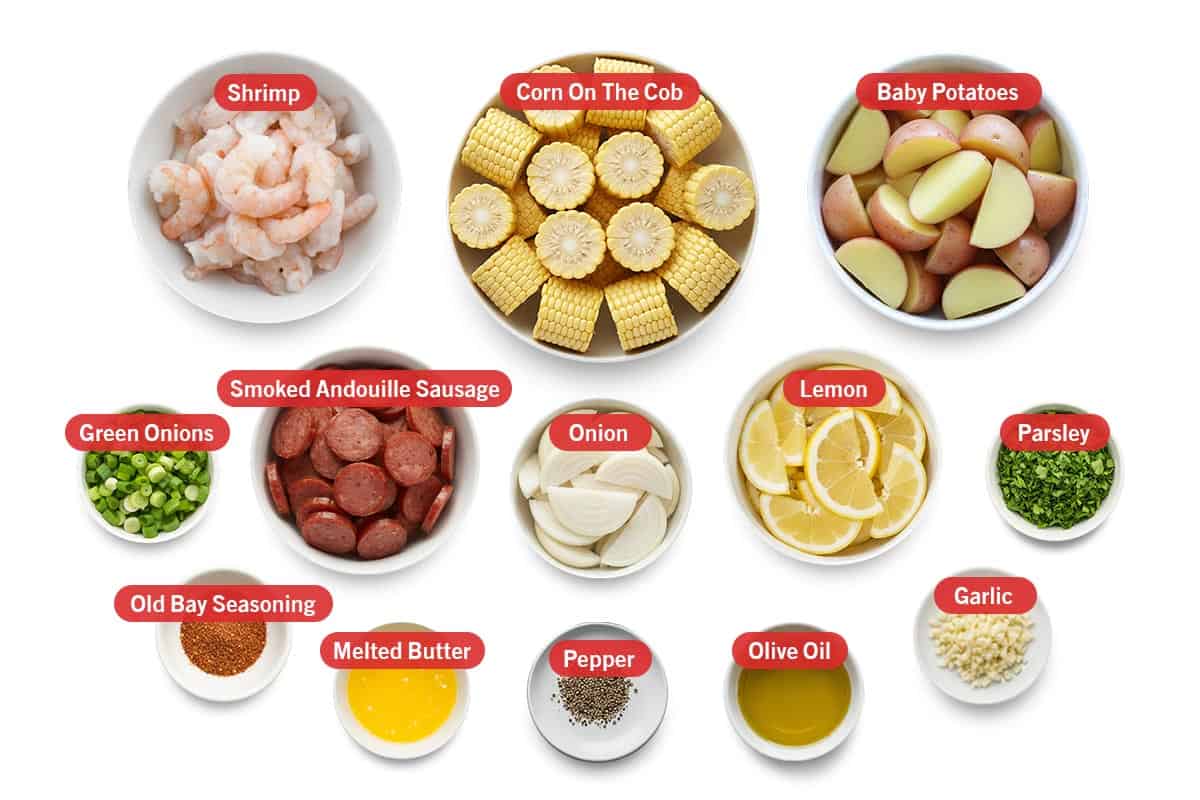 Top shot of ingredients: Shrimp, corn on the cob, baby potatoes, green onions, Smoked Andouille Sausage, onion, lemon, parsley, old bay seasoning, melted butter, pepper, olive oil, and garlic.