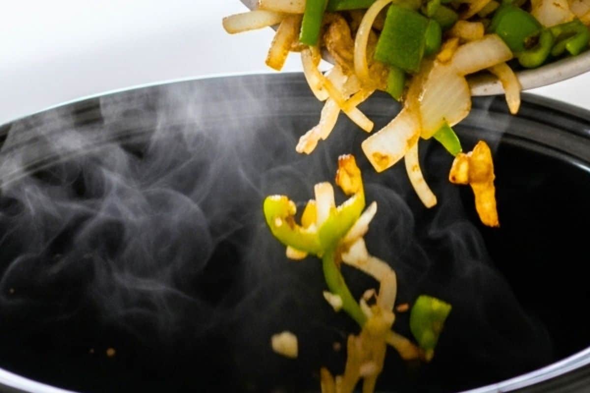 Cook the onions and green peppers in a pan and transfer the mixture to a 6-quart slow cooker bowl.