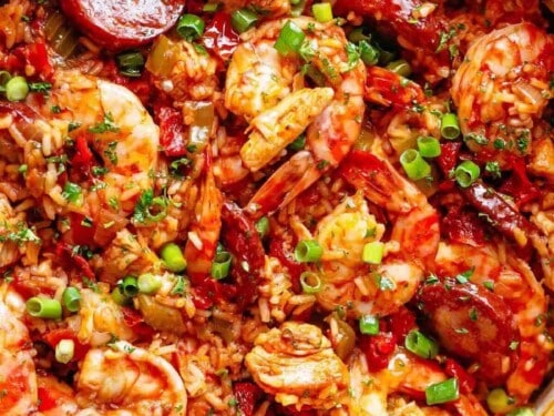 Close-up image of a colorful, freshly prepared jambalaya with shrimp and sausage, cooked in a white pot, ready to be served.