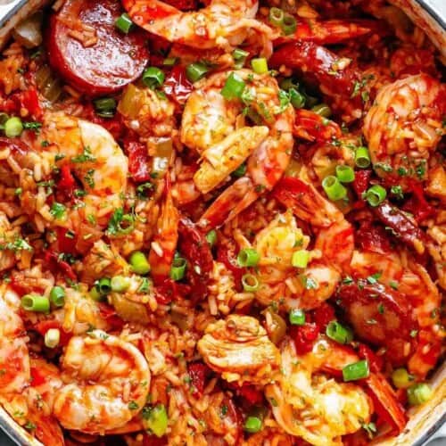 Close-up image of a colorful, freshly prepared jambalaya with shrimp and sausage, cooked in a white pot, ready to be served.