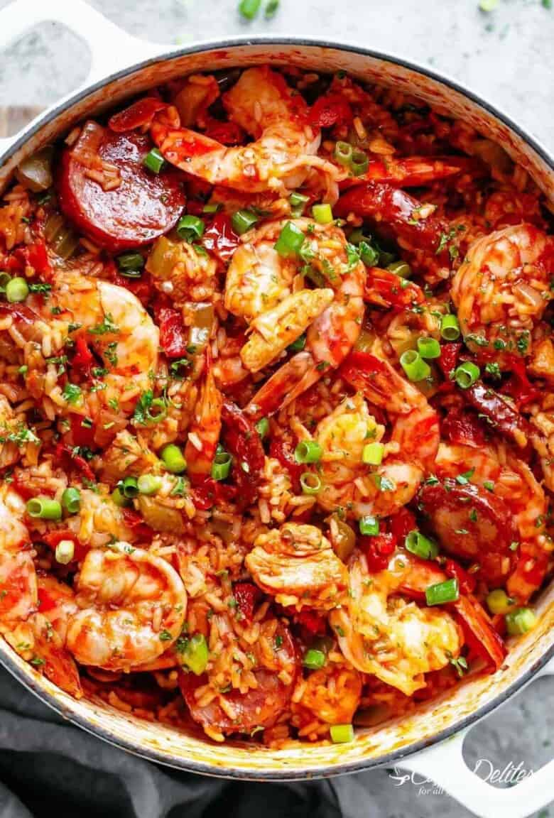 Close-up image of a colorful, freshly prepared jambalaya with shrimp and sausage, cooked in a white pot, ready to be served.