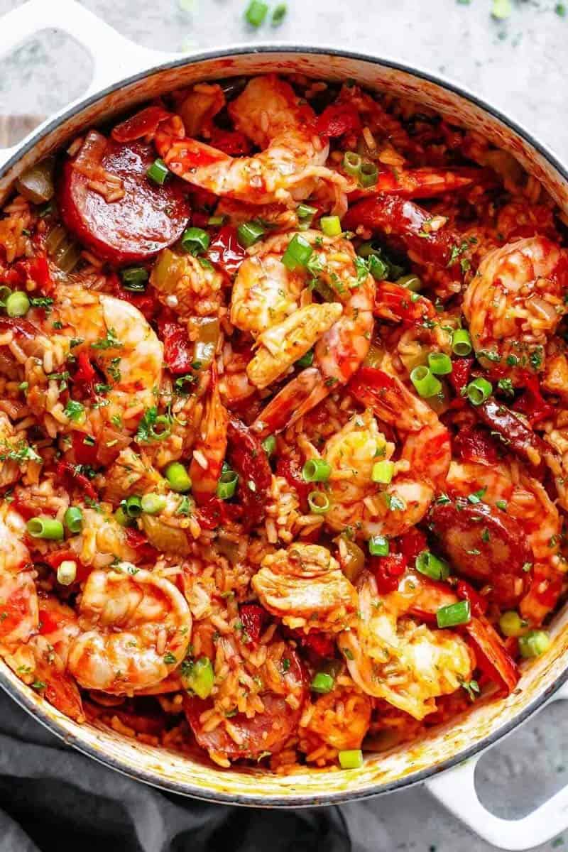 Close-up image of a colorful, freshly prepared jambalaya with shrimp and sausage, cooked in a white pot, ready to be served.