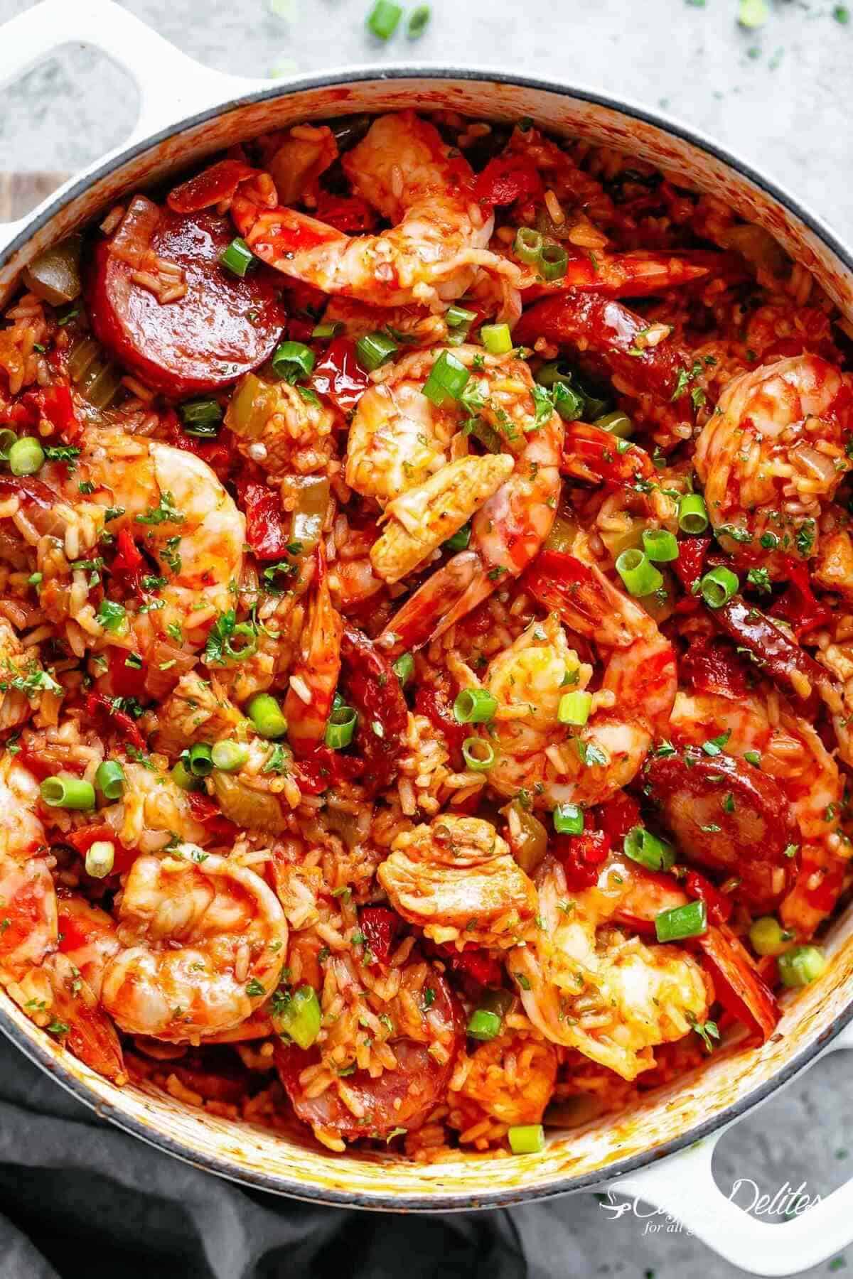 Close-up image of a colorful, freshly prepared jambalaya with shrimp and sausage, cooked in a white pot, ready to be served.