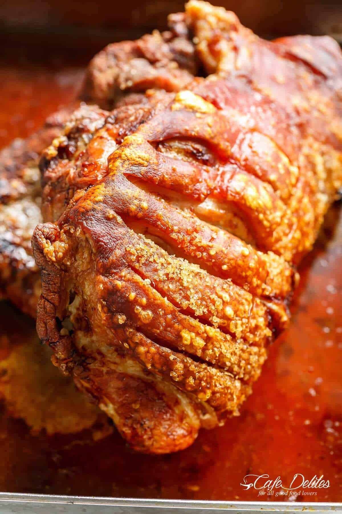 Close-up image of the beautifully cooked pork roast, just taken out of the oven, with crispy crackling in sharp focus.