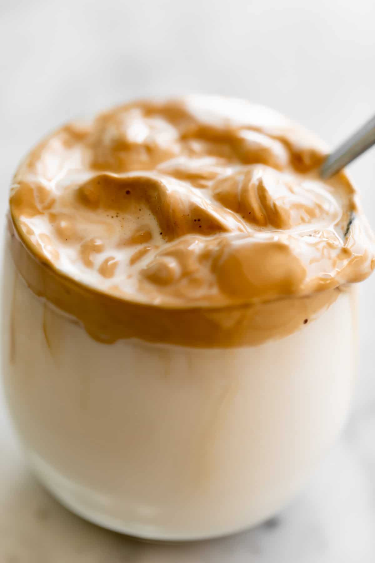 Whipped coffee being mixed into a glass of milk. 