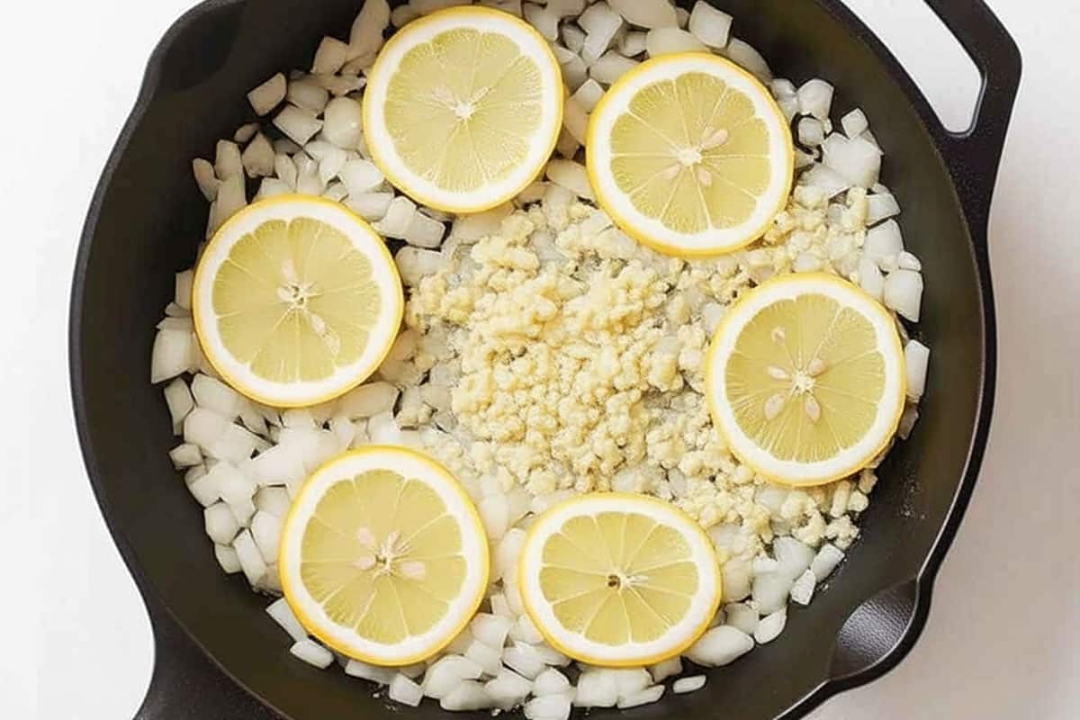 Lemon, onion, and garlic in the bottom of a large cast-iron skillet.