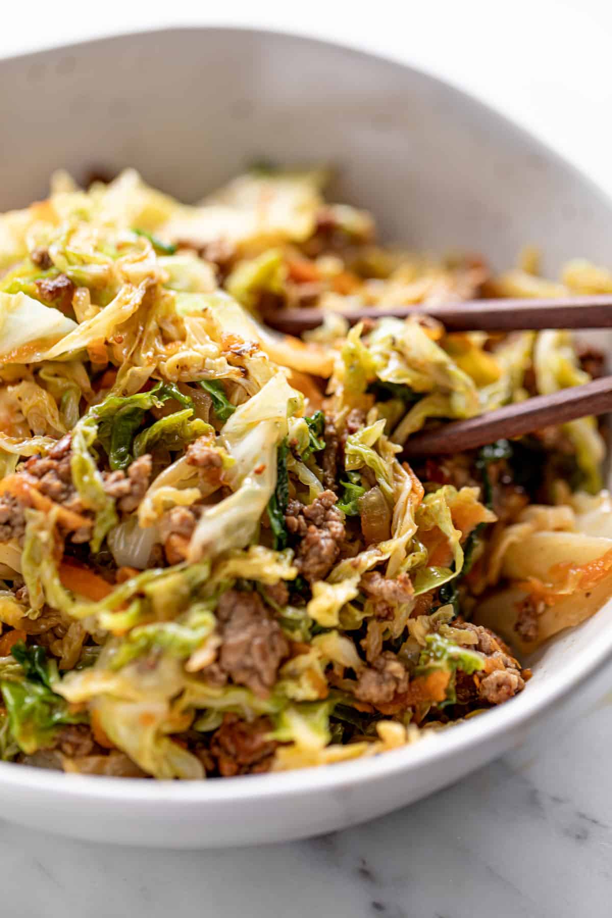 Ground Beef in a bowl with cabbage, served with chop sticks.