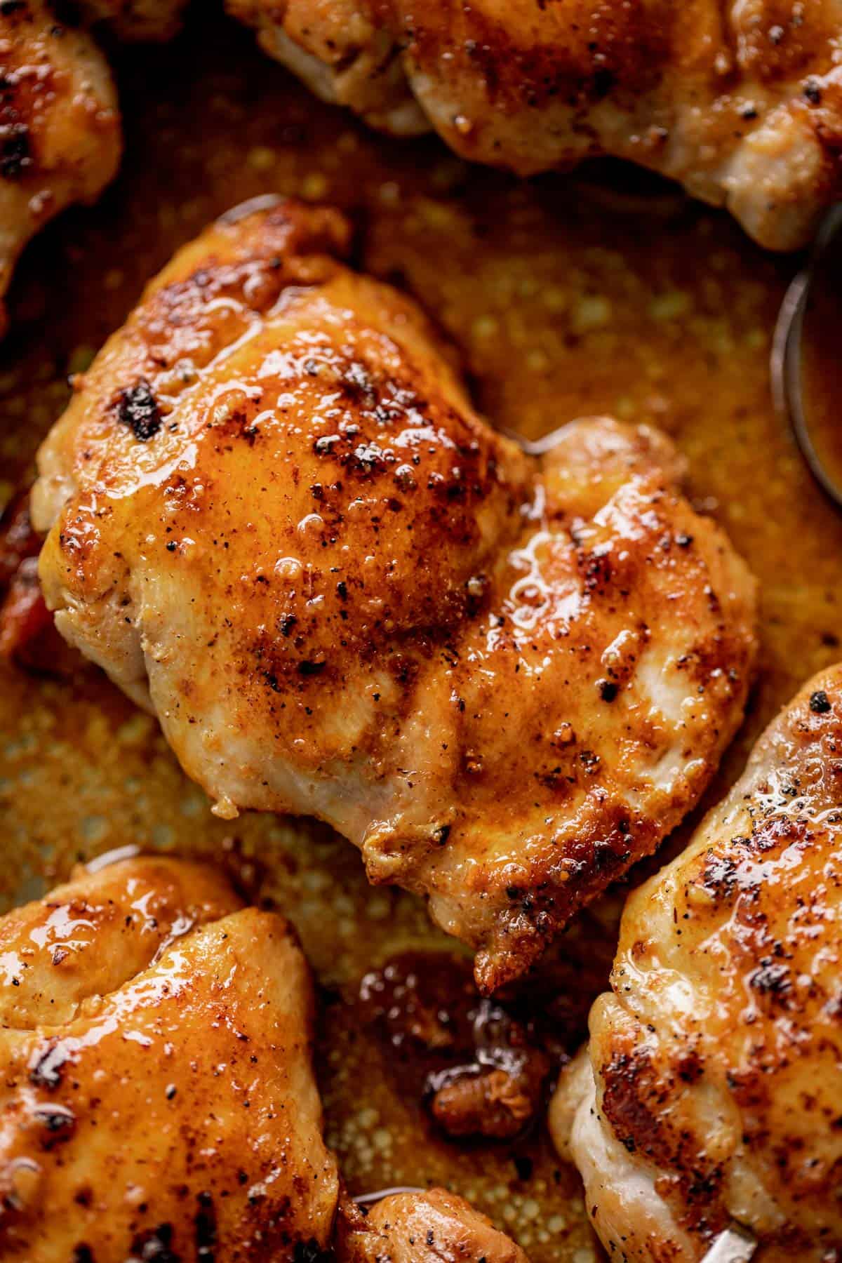 Close up of boneless chicken thighs in sauce.
