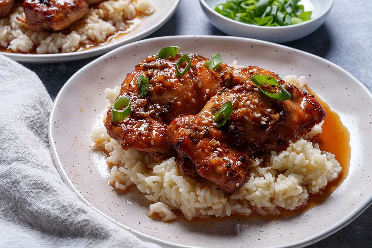 Image of the plated chicken thighs served over a bed of rice.