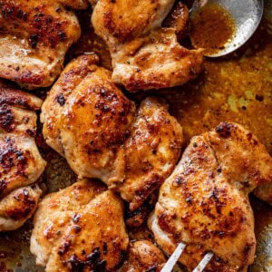 Crispy boneless chicken thighs in a silver pan, being picked up by a fork kitchen.