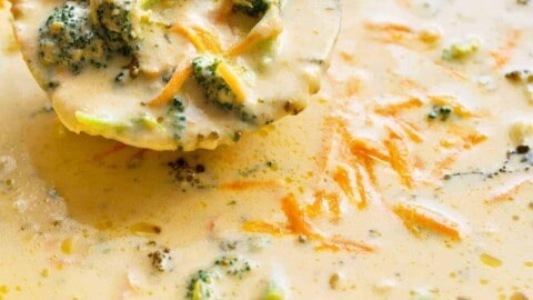 A ladle scooping up creamy broccoli cheese soup from a steaming pot.