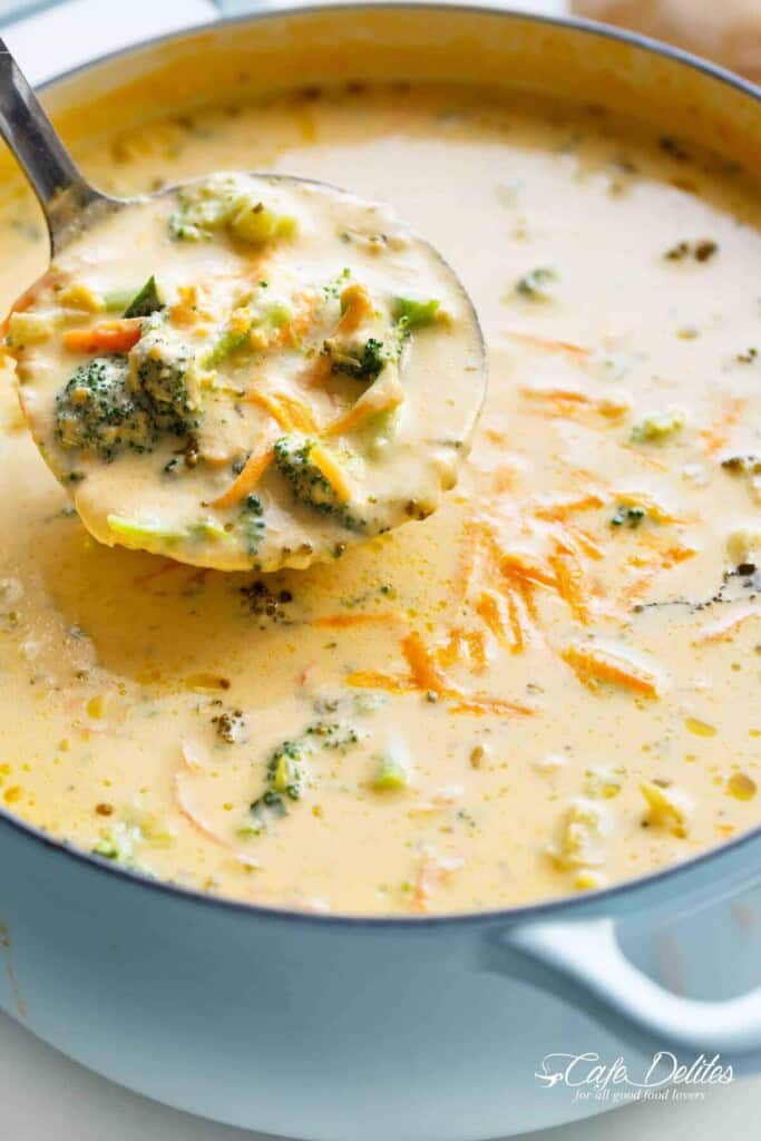 A ladle scooping up creamy broccoli cheese soup from a steaming pot.