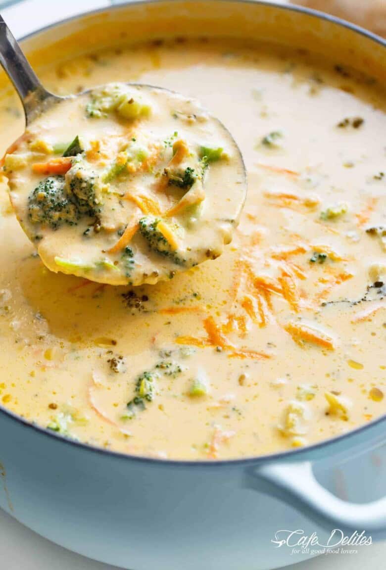 A ladle scooping up creamy broccoli cheese soup from a steaming pot.