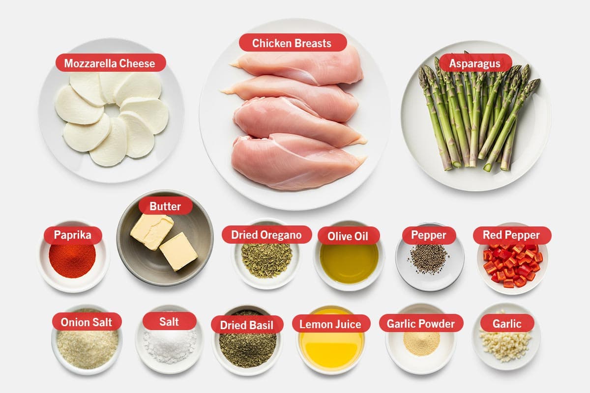 Top shot of ingredients: Mozzarella cheese, chicken breasts, asparagus, paprika, butter, dried oregano, olive oil, pepper, red pepper, onion salt, salt, dried basil, lemon juice, garlic powder, and garlic.