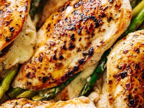 An overhead image of four asparagus and mozzarella cheese stuffed chicken breasts in a white casserole dish | cafedelites.com
