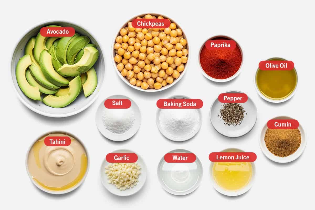 Top shot of ingredients: Avocado, chickpeas, paprika, olive oil, salt, baking soda, pepper, cumin, tahini, garlic, water, and lemon juice.