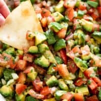 A bowl of avocado salsa with a tortilla chip | cafedelites.com