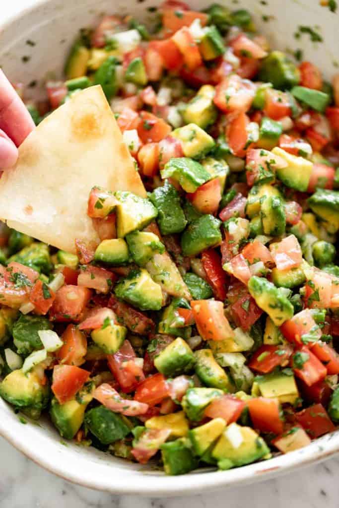 A bowl of avocado salsa with a tortilla chip | cafedelites.com