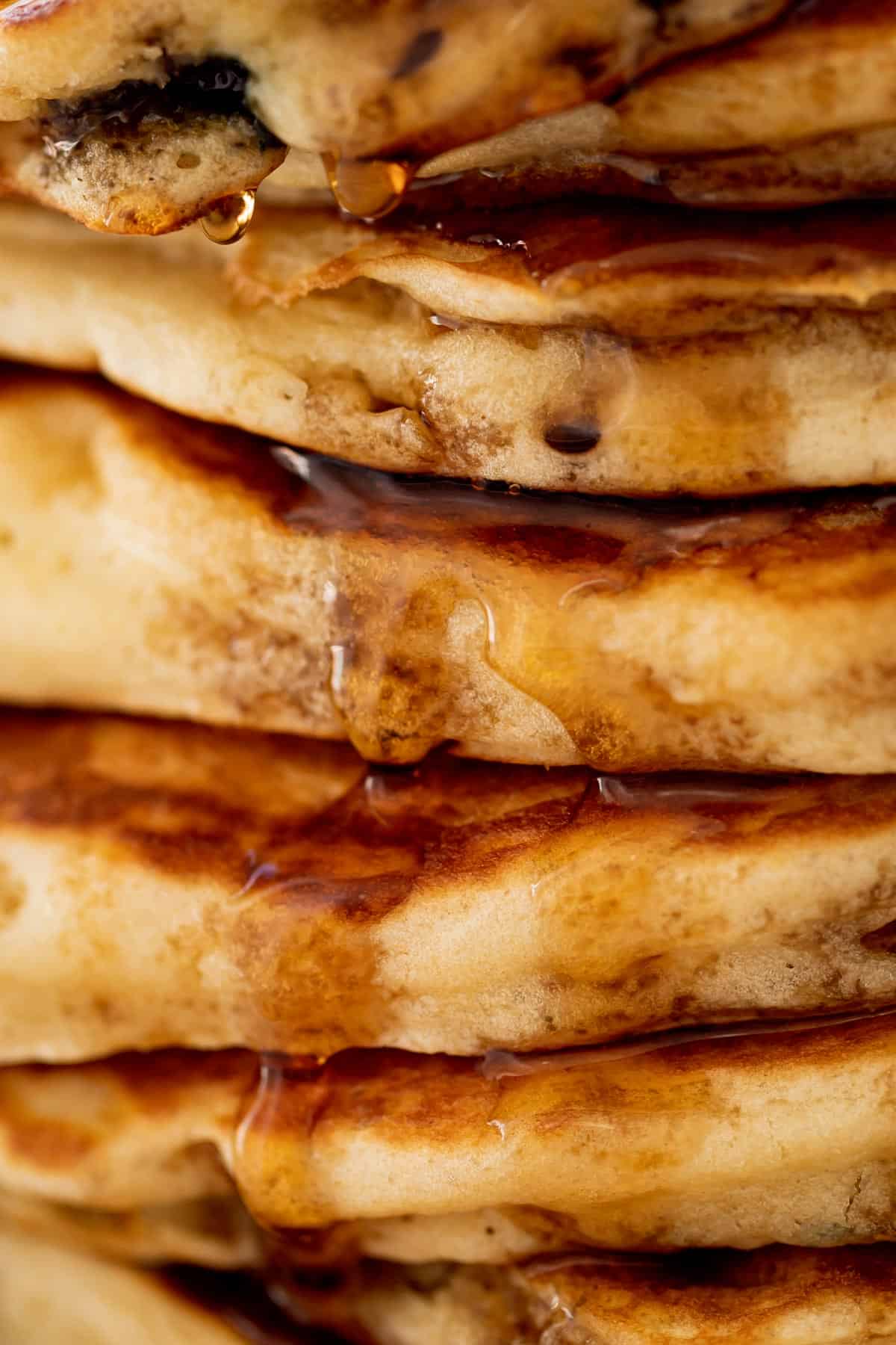 A close up stack of Blueberry Pancakes on a plate with maple syrup. | cafedelites.com