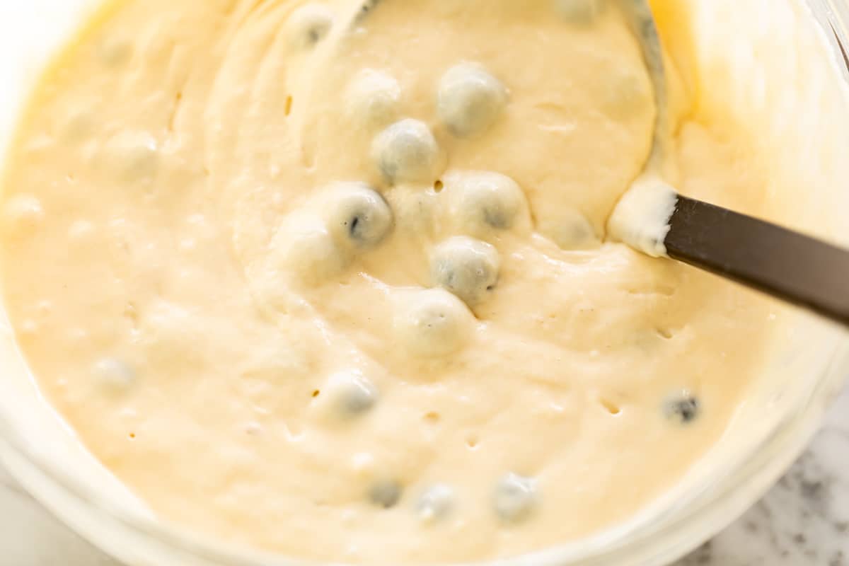 Blueberry pancake batter in a bowl with a ladle.