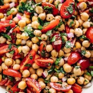 Chickpea Tomato Salad in a white bowl on a white marble table background.