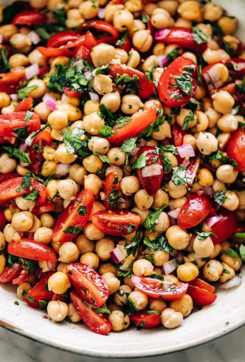 Chickpea Tomato Salad in a white bowl on a white marble table background | cafedelites