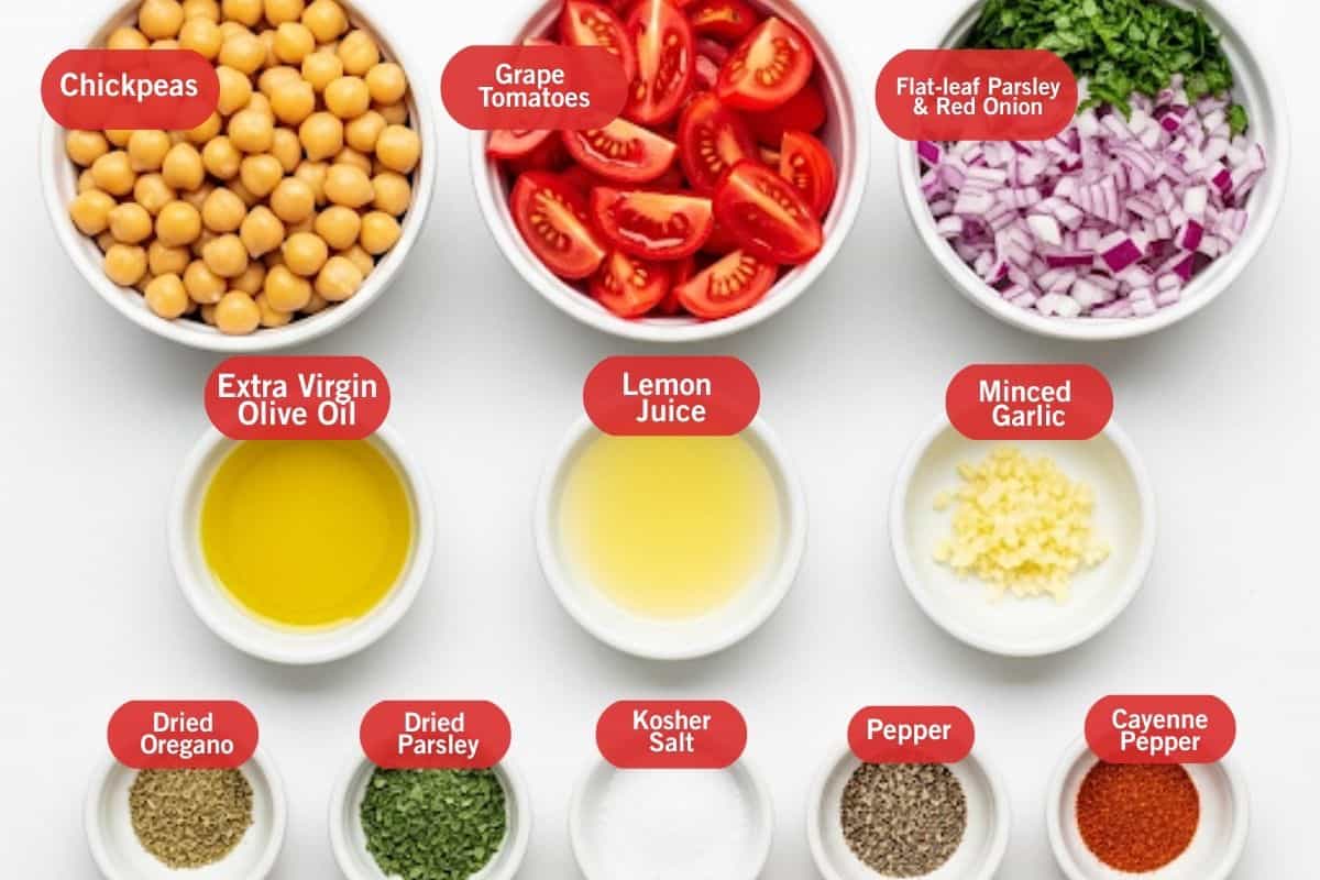 Flat lay photo of ingredient shot of chickpeas, grape tomatoes, flat-leaf parsley and red onion, extra virgin olive oil, lemon juice, minced garlic, dried oregano, dried parsley, kosher salt, pepper, cayenne pepper