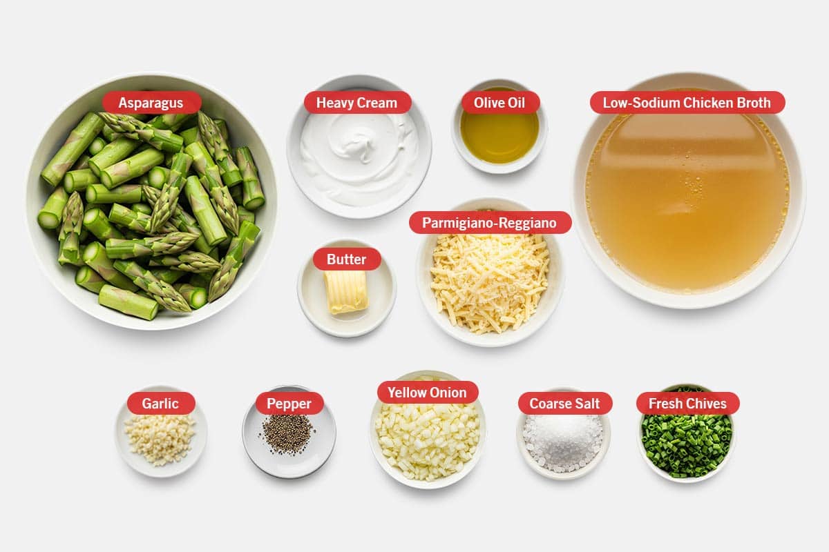 Top view of ingredients: Asparagus, heavy cream, olive oil, low-sodium chicken broth, butter, Parmigiano-Reggiano, garlic, pepper, yellow onion, coarse salt, and fresh chives.