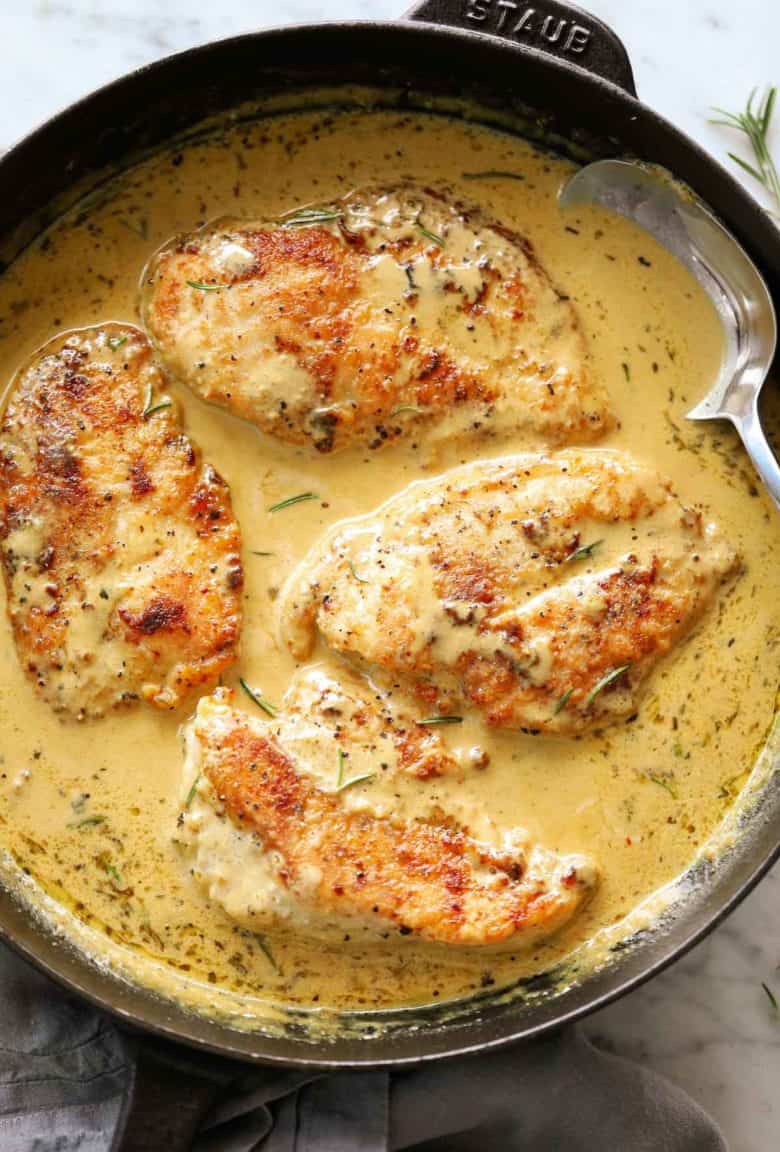 Creamy mustard chicken breasts in a black Staub skillet with a metal spoon | cafedelites.com