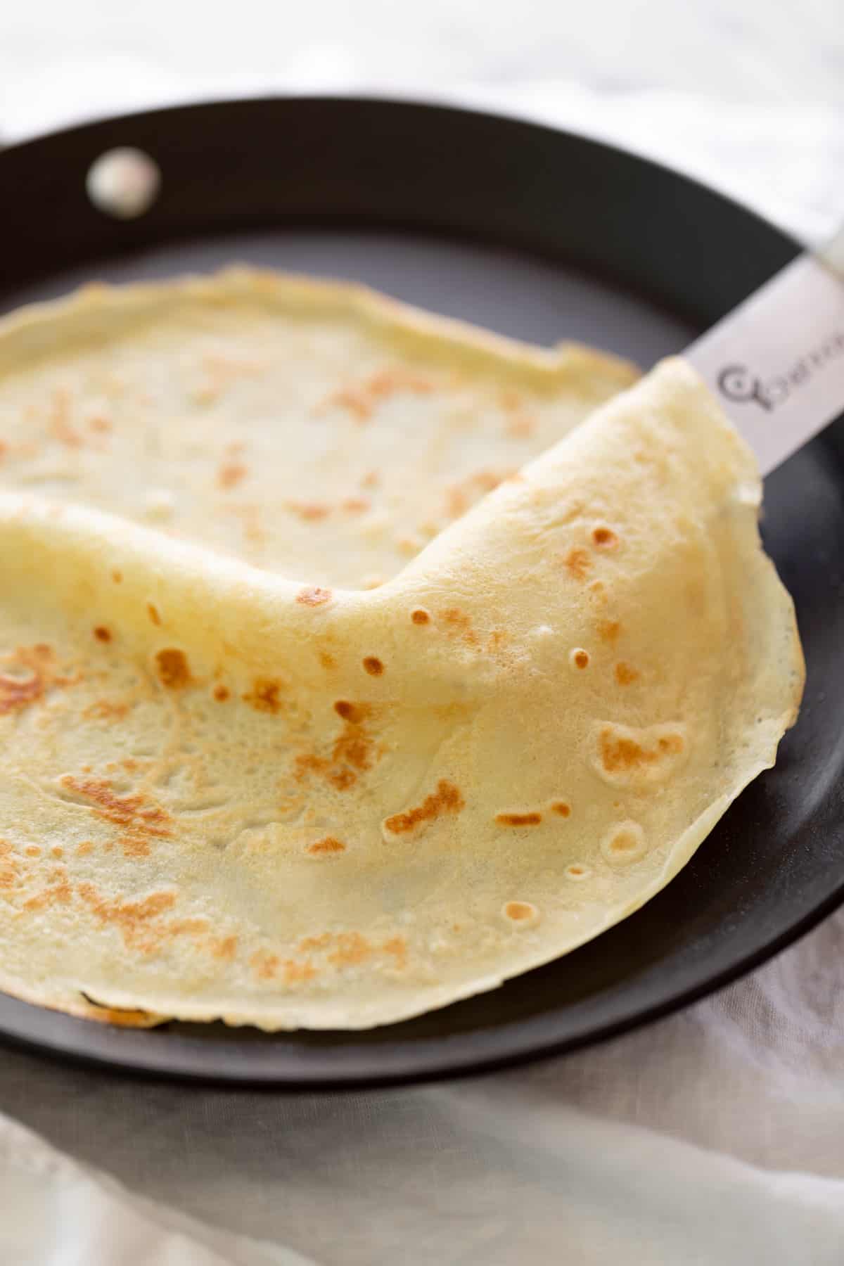 Flipping crepes in a nonstick pan with a metal spatula | cafedelites.com