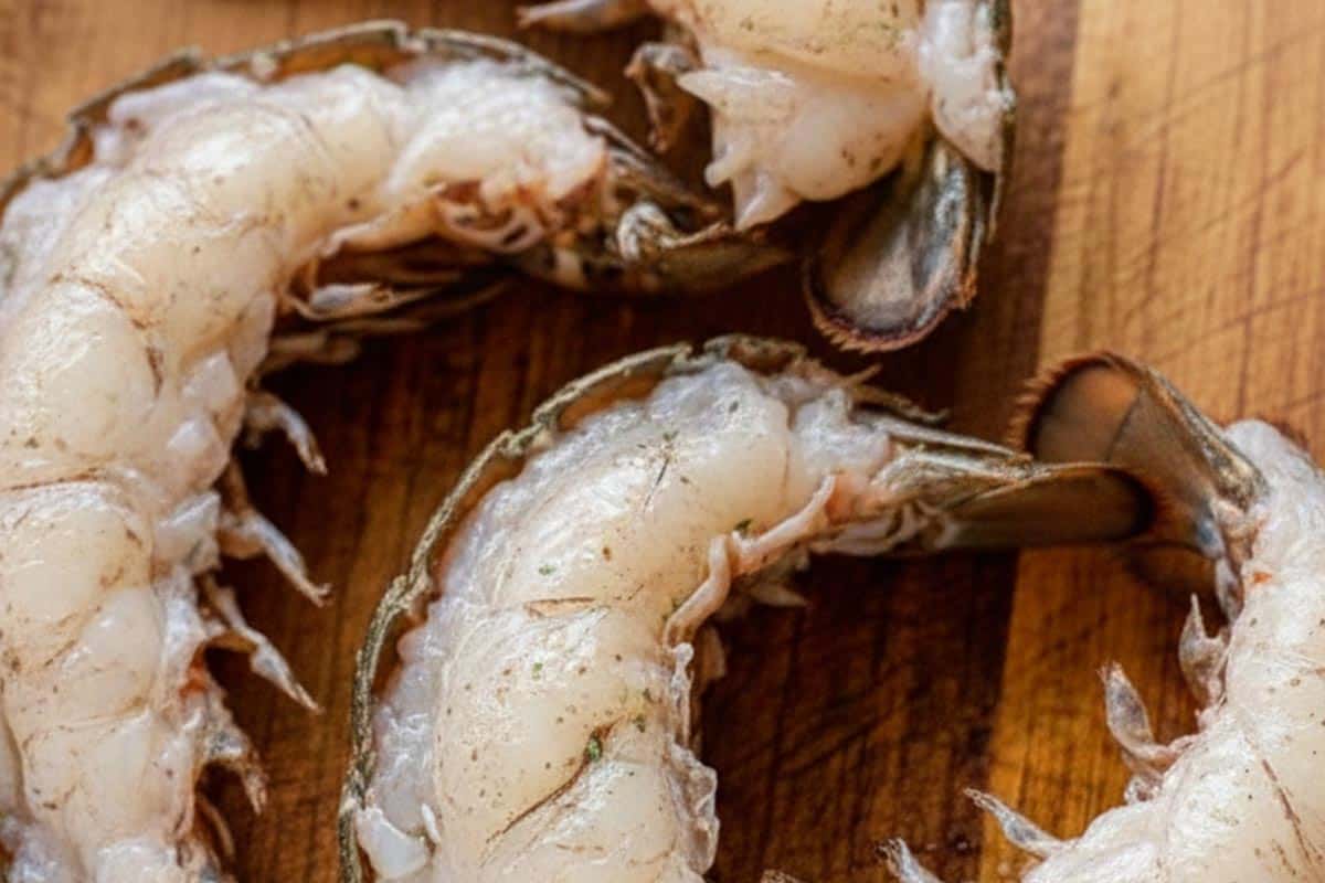 Lobster tails on a wooden cutting board.