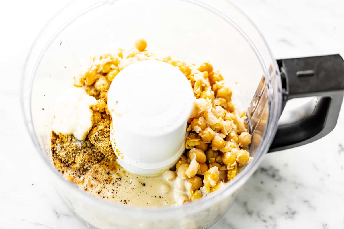 Ingredients for hummus in a food processor bowl ready to be blended.