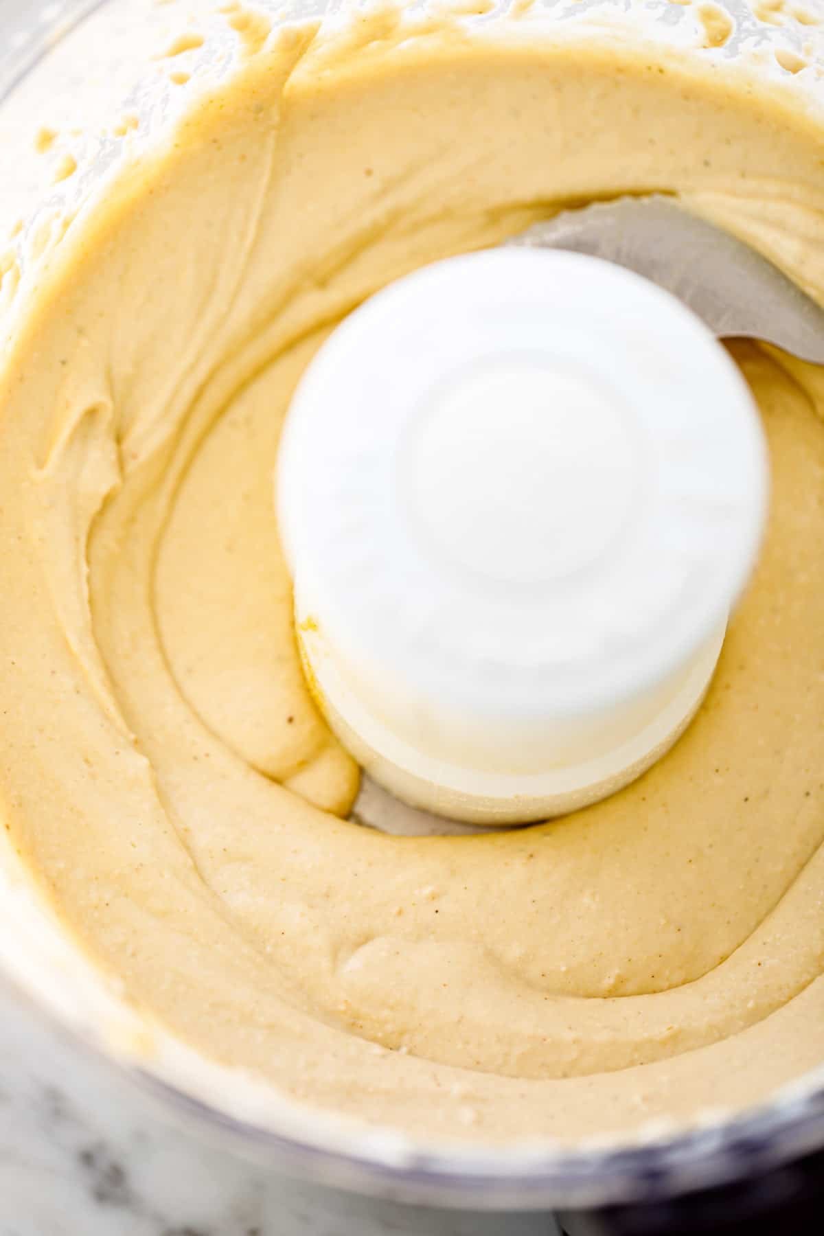 Hummus processed in a food processor bowl ready to be blended.