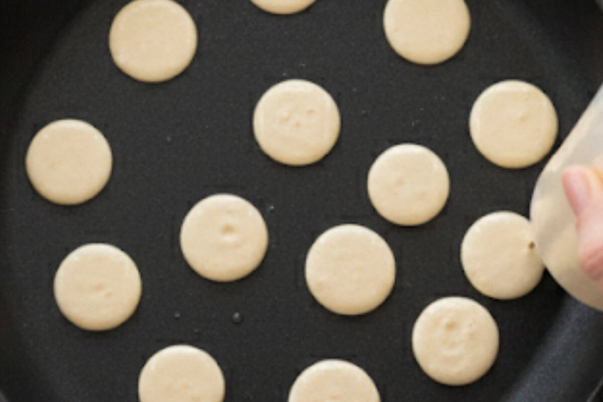 Squeeze small dots of batter onto the pan, cook until bubbles form on top.