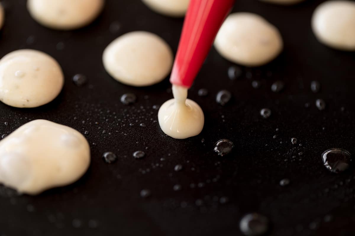 Placer la pâte à crêpes en petites formes de mini crêpes à l'aide d'une bouteille à presser sur une poêle antiadhésive légèrement graissée à l'huile.