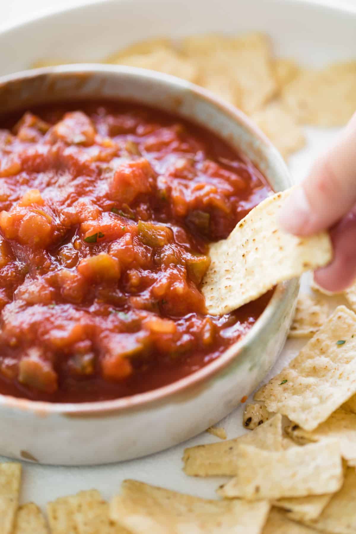 Dipping a corn chip into a bowl of salsa.