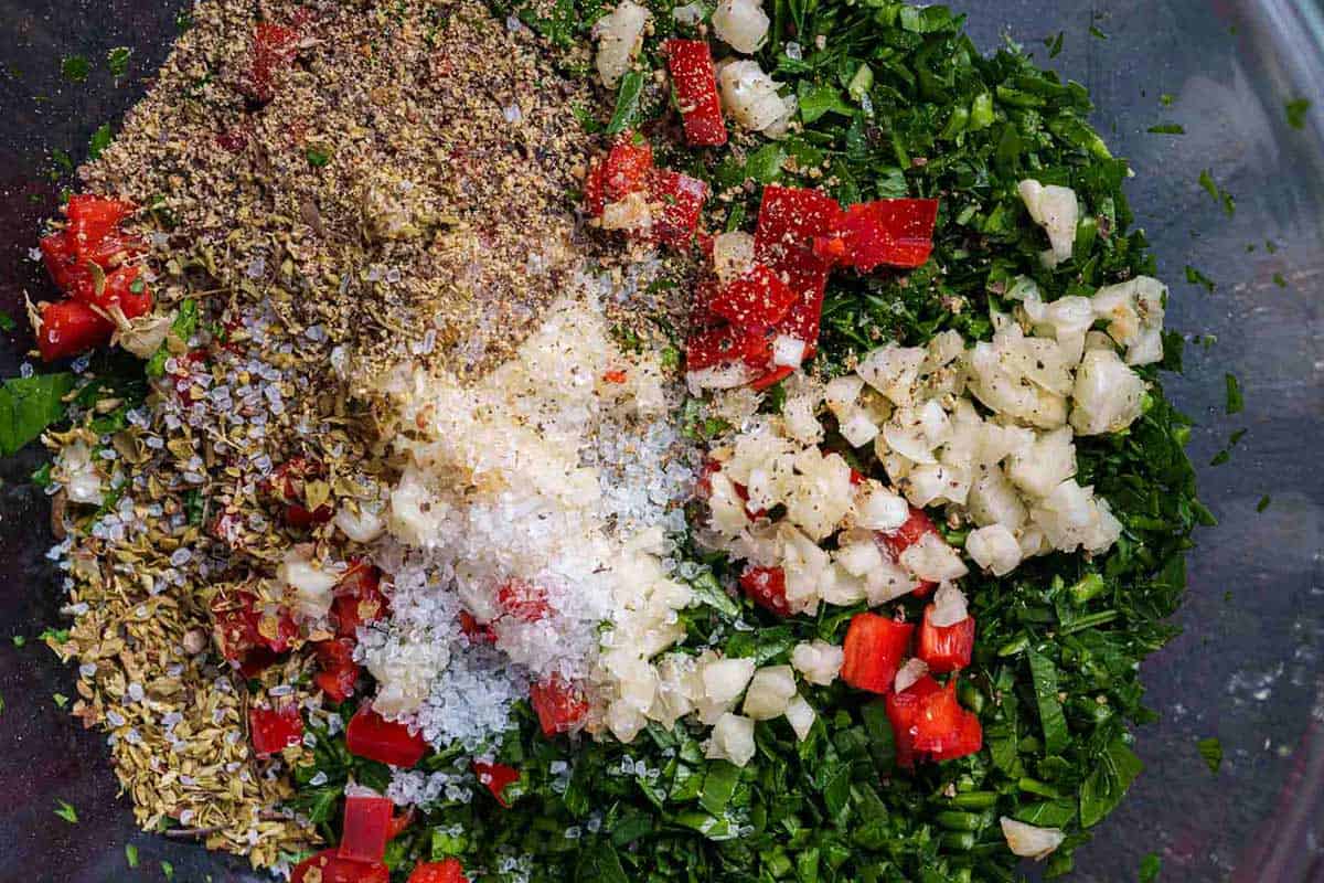 Finely chop parsley, garlic, and red chili, and combine them in a clear bowl with a pinch of salt and pepper.