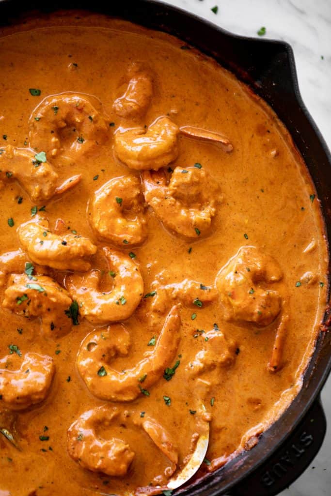 A flavour-filled shrimp curry with an aromatic coconut curry sauce cooks in no time from scratch! Shrimp curry in a black skillet with a metal serving spoon | cafedelites.com