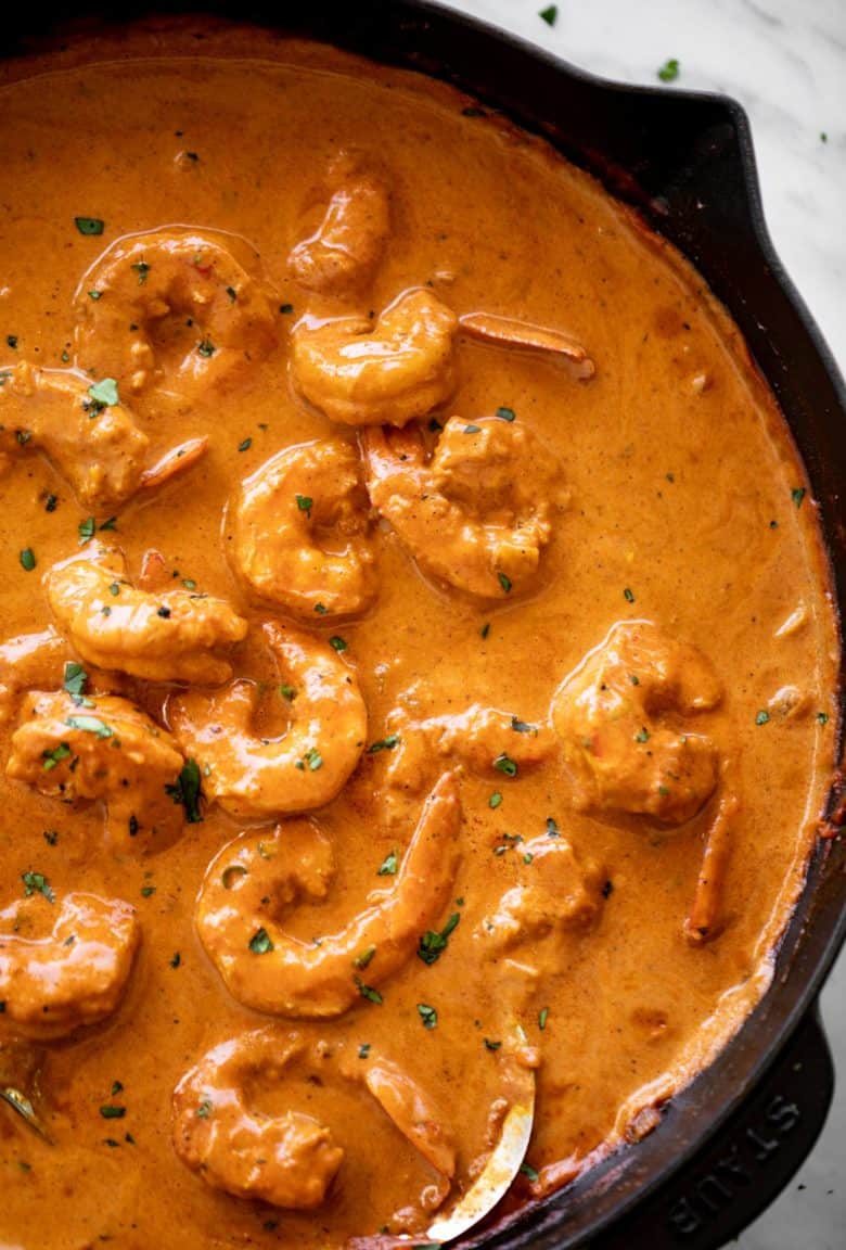 A flavour-filled shrimp curry with an aromatic coconut curry sauce cooks in no time from scratch! Shrimp curry in a black skillet with a metal serving spoon | cafedelites.com