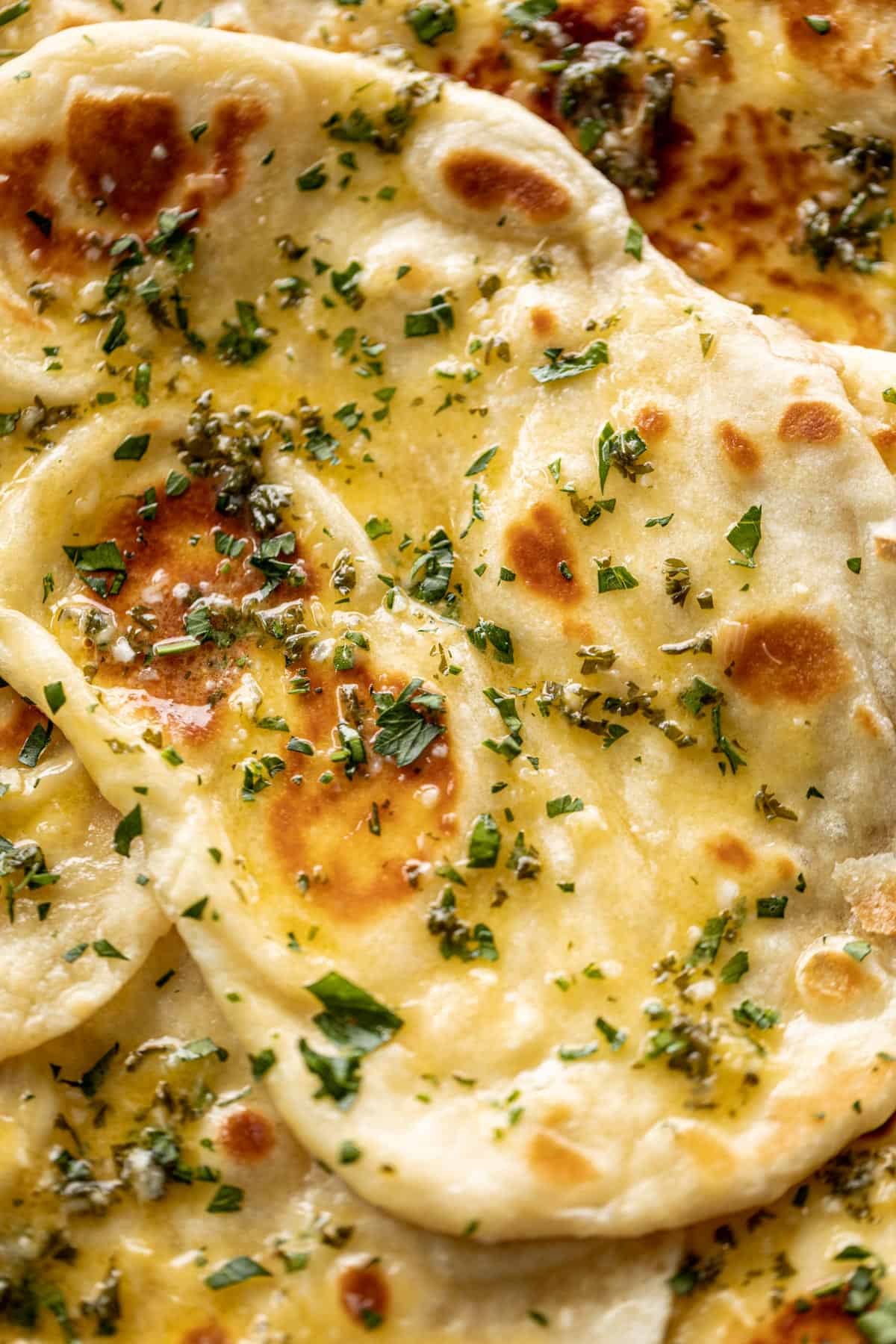 Buttery Garlic Naan Bread close up brushed with melted garlic butter and garnished with fresh chopped cilantro | cafedelites.com