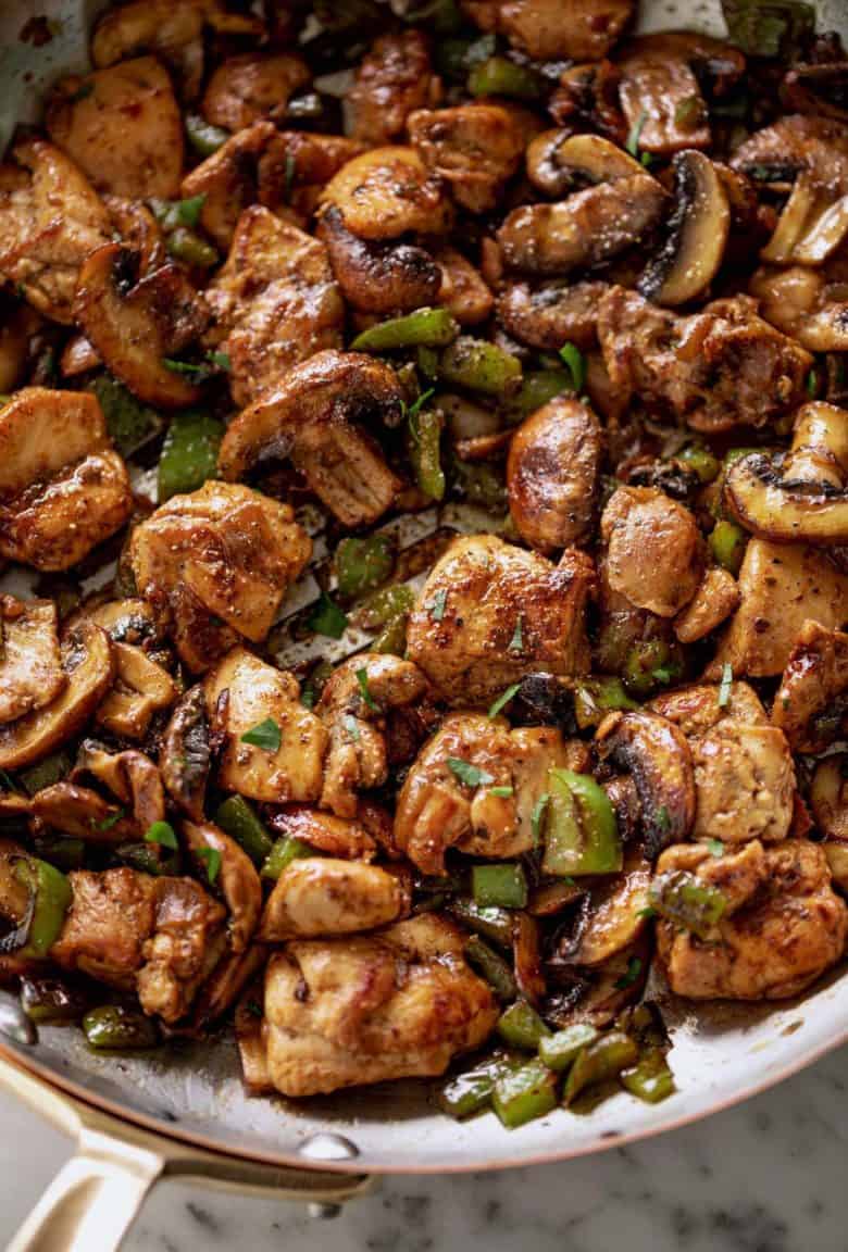 Garlic Mushroom Chicken Bites cook in no time at all! An easy dinner recipe cooked in a silver pan or skillet with a wooden spoon. | cafedelites.com