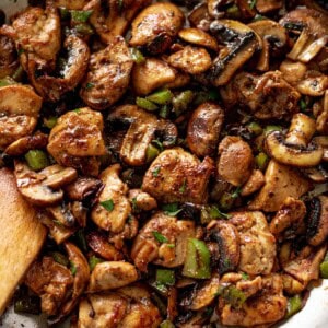 Garlic Mushroom Chicken Bites cook in no time at all! An easy dinner recipe cooked in a silver pan or skillet with a wooden spoon.
