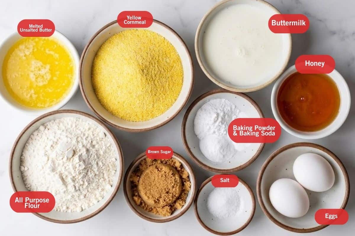 Flat lay photo of melted butter, yellow cornmeal, butter milk, honey, baking powder and baking soda, eggs, salt, brown sugar, all purpose flour