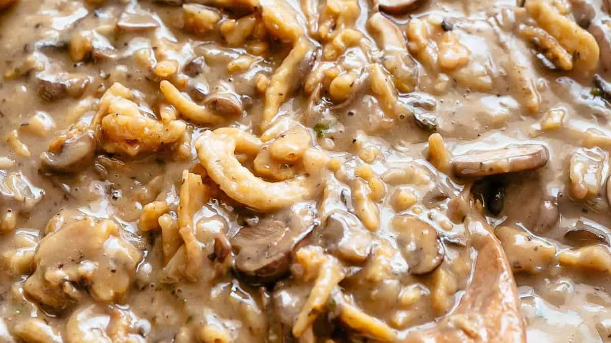 A skillet with mushroom soup and fried onion rings for green bean casserole